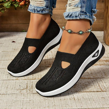 Scarpe da ginnastica nere da donna con suola bianca, design traforato, indossate con jeans strappati e cavigliera con pietre turchesi.