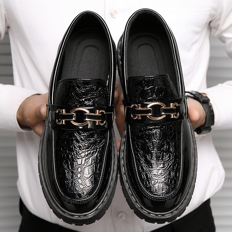 Scarpe mocassini uomo in pelle nera lucida con motivo coccodrillo, dettagli metallici dorati, indossate da persona in camicia bianca.