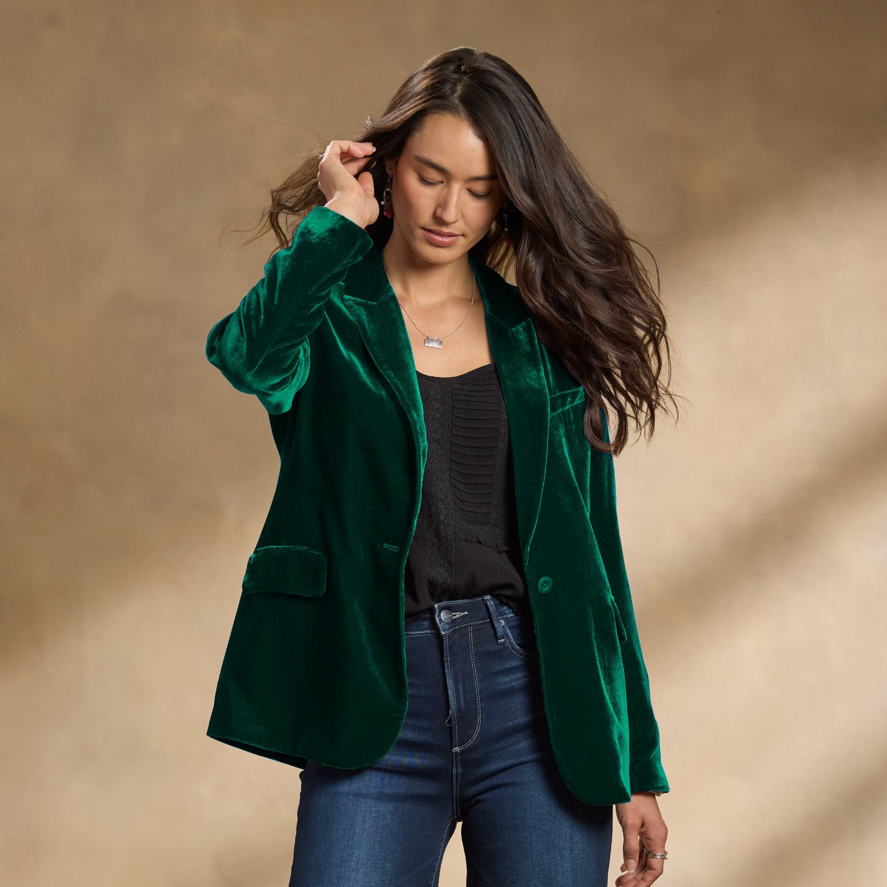 Donna con giacca di velluto verde, camicia nera e jeans. Moda autunnale elegante, abbigliamento casual chic, tendenze moda 2023.