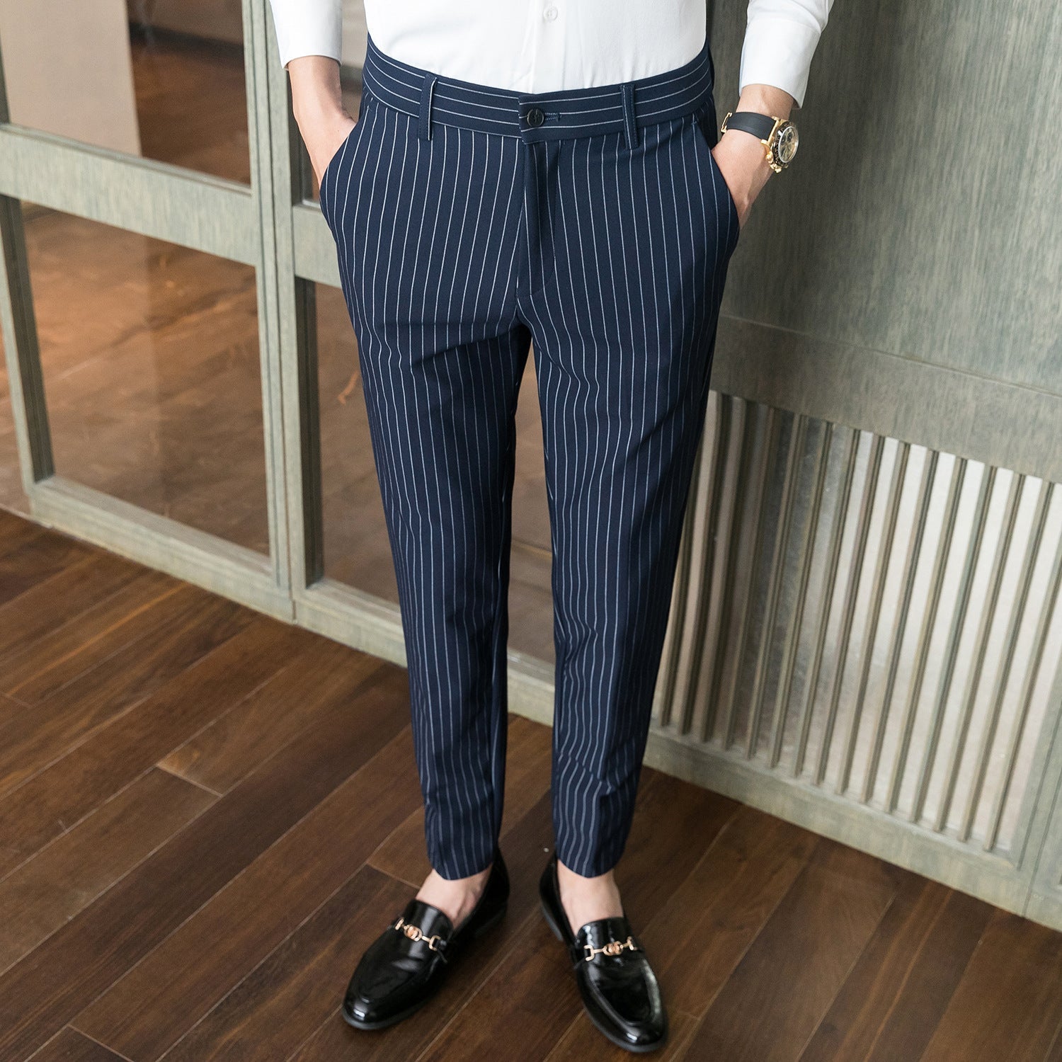 Pantaloni eleganti a righe blu e bianche, indossati con mocassini neri e camicia bianca; moda uomo, abbigliamento formale, stile moderno.