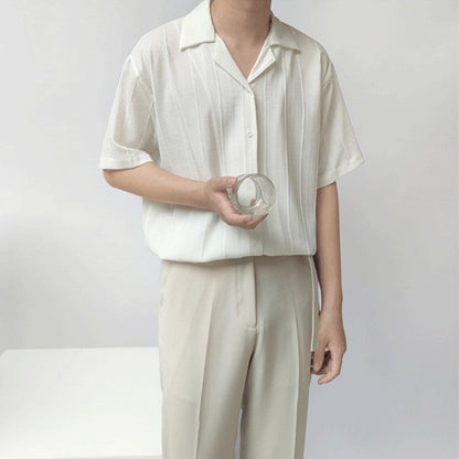 Uomo in camicia bianca e pantaloni beige tiene un bicchiere trasparente. Moda minimalista estiva, abbigliamento casual elegante.