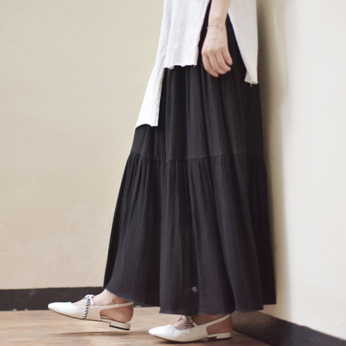 Donna con gonna lunga nera e camicia bianca, scarpe bianche eleganti, moda minimalista, stile casual chic, abbigliamento femminile moderno.