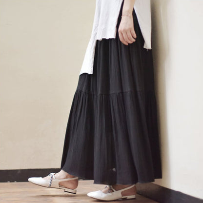 Donna con gonna lunga nera e camicia bianca, scarpe bianche eleganti, moda minimalista, stile casual chic, abbigliamento femminile moderno.