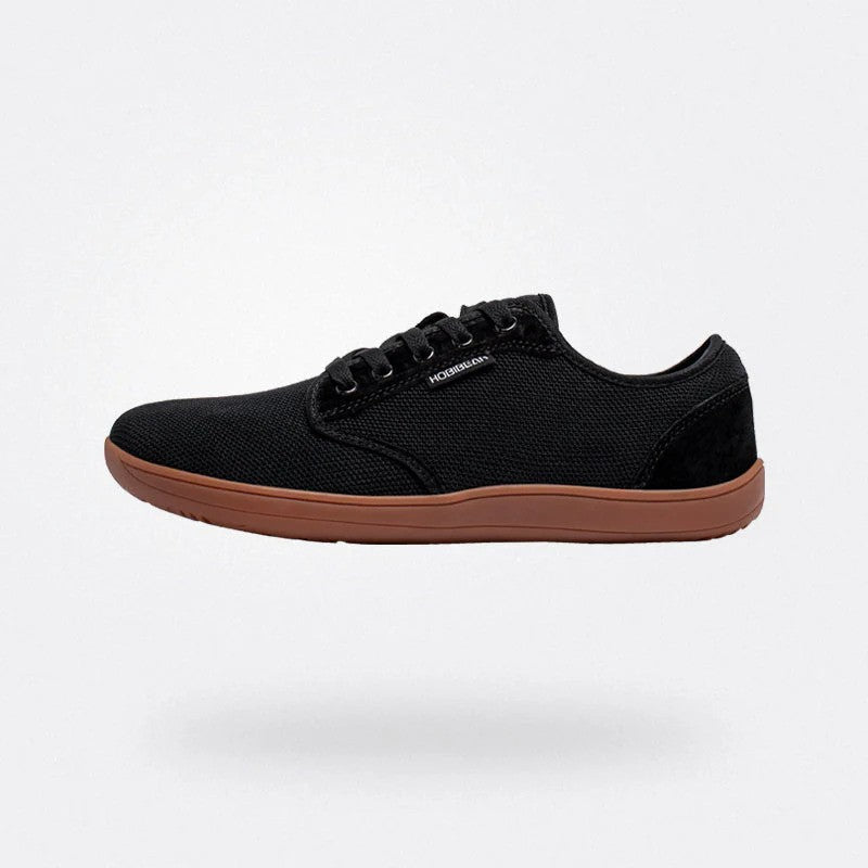 Scarpa casual nera da uomo, suola marrone, design minimalista, tessuto traspirante, perfetta per look quotidiani e comfort.