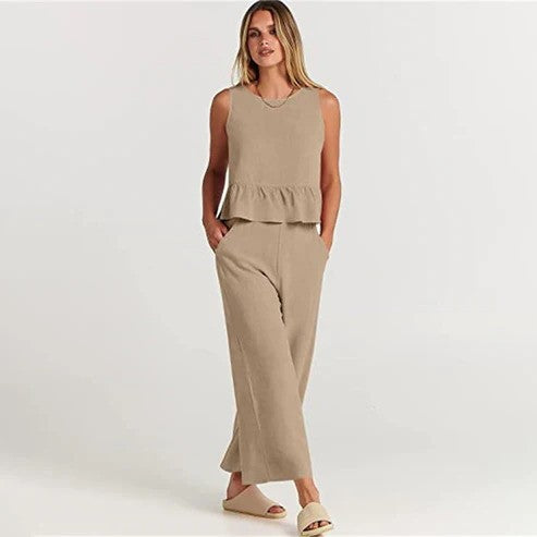 Donna in abbigliamento estivo beige, top senza maniche e pantaloni larghi, sandali chiari. Moda casual elegante, look estivo femminile.