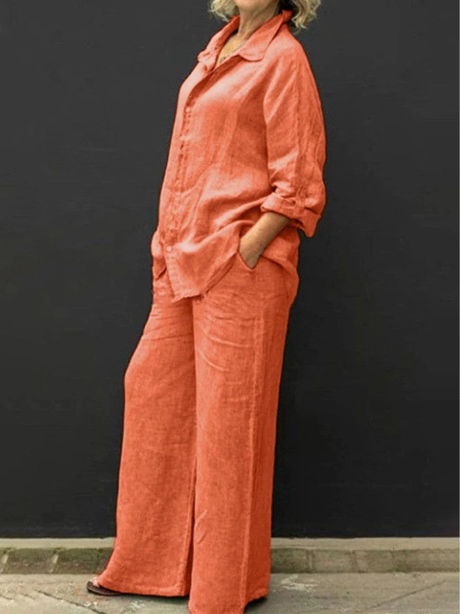 Donna in abito di lino arancione, camicia e pantaloni larghi, sfondo nero. Moda estiva, abbigliamento casual elegante, stile rilassato.