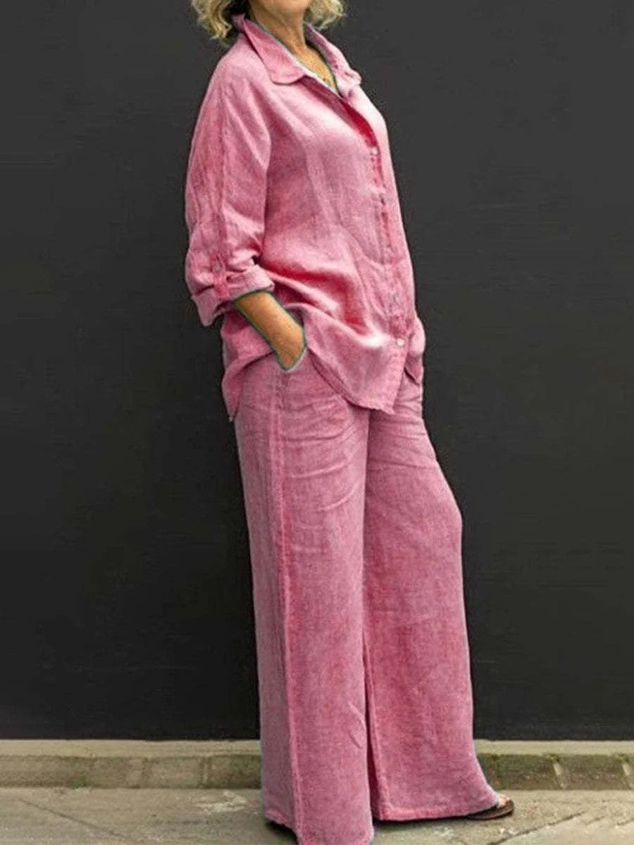 Donna in abbigliamento casual, indossa un completo rosa in lino con camicia e pantaloni larghi, sfondo nero. Moda femminile, stile estivo.