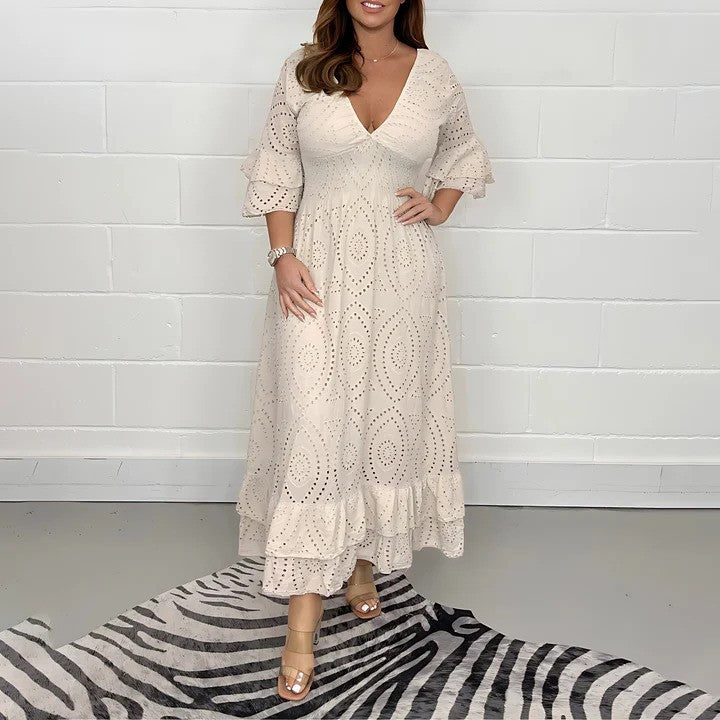 Abito lungo bianco in pizzo traforato con maniche a volant, indossato da una donna su tappeto zebrato. Moda elegante, abbigliamento estivo femminile.