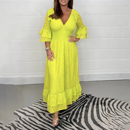 Abito lungo giallo con maniche a tre quarti e dettagli traforati, indossato da una donna su tappeto zebrato. Moda estiva elegante e vivace.