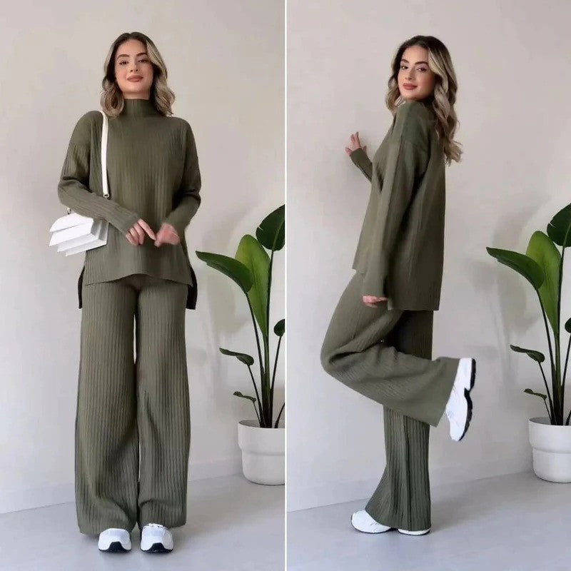 Donna in abbigliamento casual verde oliva, maglione e pantaloni a coste, con borsa bianca e scarpe da ginnastica, posa davanti a piante d'appartamento.