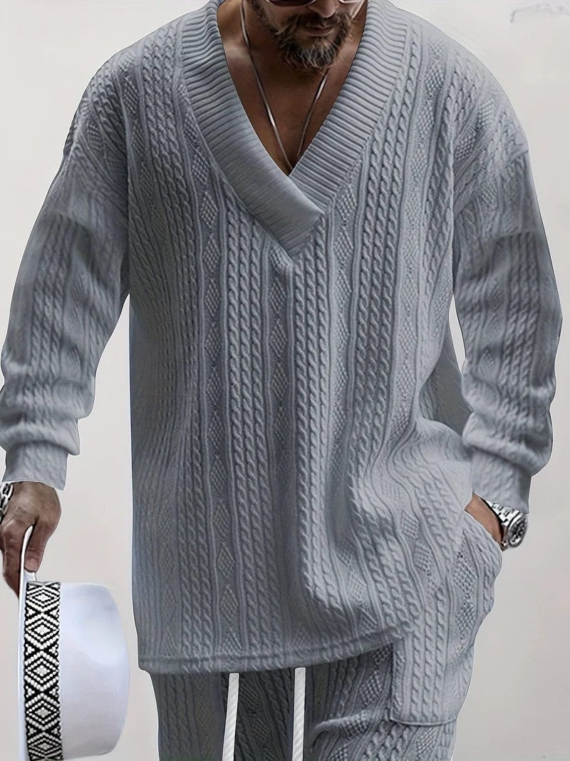 Maglione uomo grigio a maglia grossa con scollo a V, abbinato a pantaloni coordinati. Stile casual elegante, moda maschile autunnale.