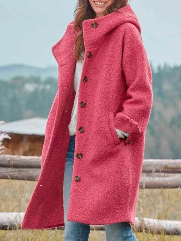 Donna con cappotto rosa in lana, bottoni marroni, in un paesaggio naturale. Moda autunnale, abbigliamento caldo, stile casual.