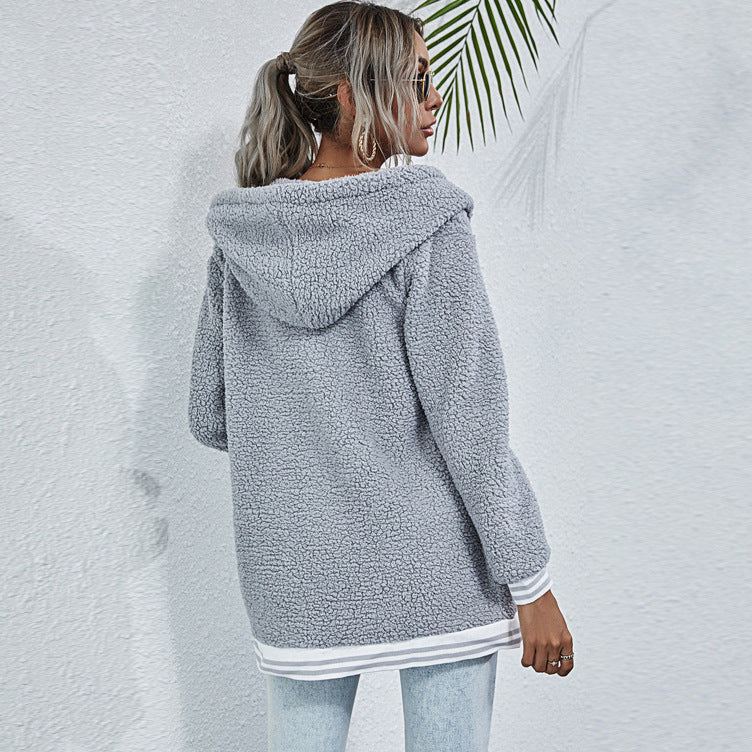 Donna con cappotto in pile grigio, cappuccio, jeans chiari, sfondo bianco. Moda autunnale, abbigliamento casual, stile urbano.