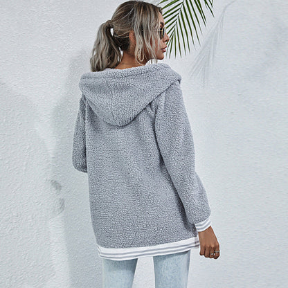 Donna con cappotto in pile grigio, cappuccio, jeans chiari, sfondo bianco. Moda autunnale, abbigliamento casual, stile urbano.