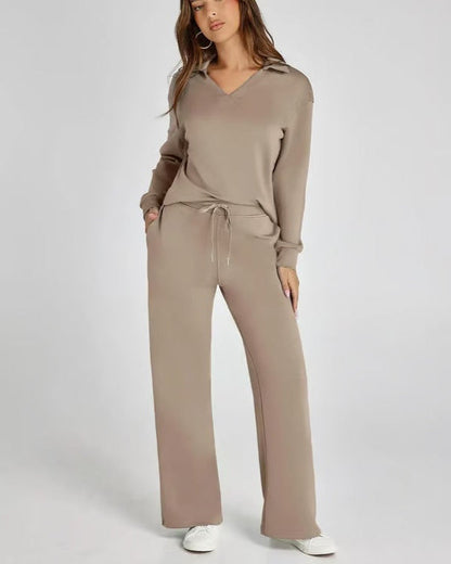 Donna in tuta beige, felpa con cappuccio e pantaloni larghi, posa casual. Abbigliamento comodo e alla moda, perfetto per il tempo libero.