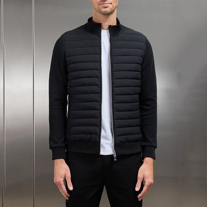 Giacca nera trapuntata da uomo, stile casual, con zip frontale, indossata su maglietta bianca. Moda maschile autunnale, abbigliamento moderno.