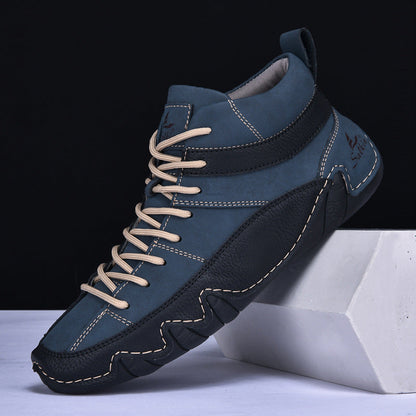 Scarpa da uomo in pelle blu con suola nera, cuciture a contrasto e lacci beige, posizionata su un cubo bianco. Design casual e moderno.