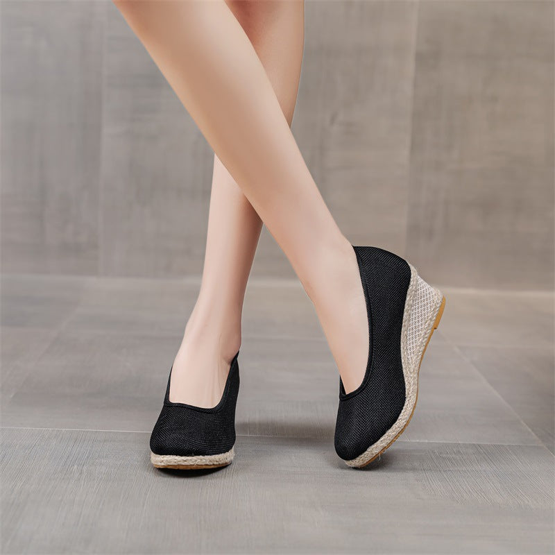 Scarpe con zeppa nere eleganti su pavimento grigio. Calzature moda donna, design moderno, comfort e stile per ogni occasione.