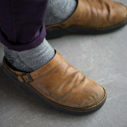 Scarpe in pelle marrone con fibbia, indossate con calzini grigi e pantaloni viola. Calzature casual, moda uomo, stile vintage.