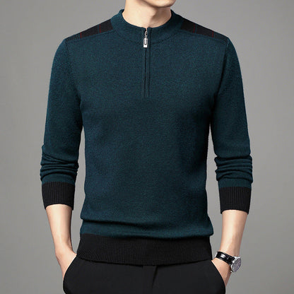 Maglione uomo verde scuro con zip corta, dettagli neri sulle spalle, polsini e orlo a coste, indossato con pantaloni neri. Moda maschile elegante.