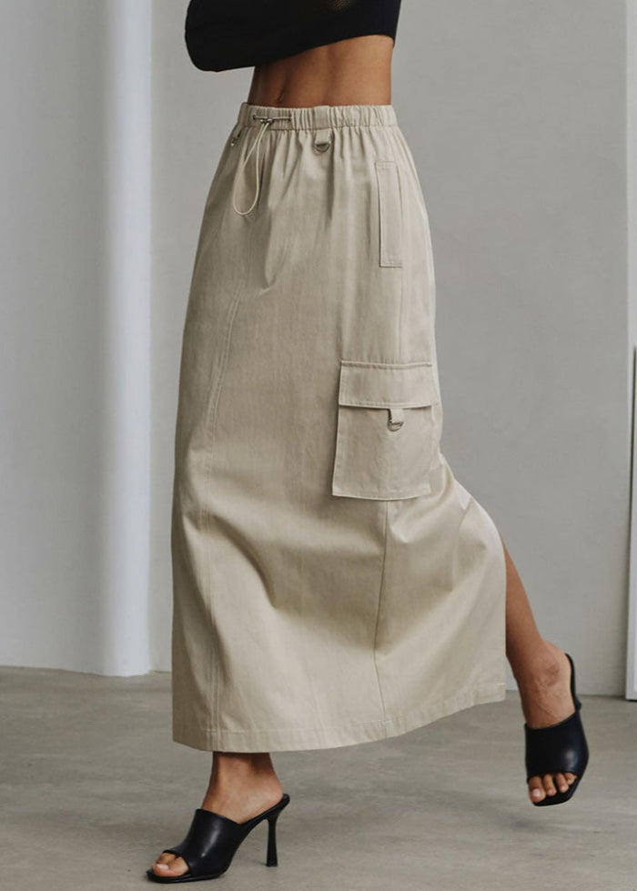 Gonna lunga beige con tasca cargo, indossata con sandali neri a tacco alto. Moda donna, abbigliamento casual chic, stile contemporaneo.