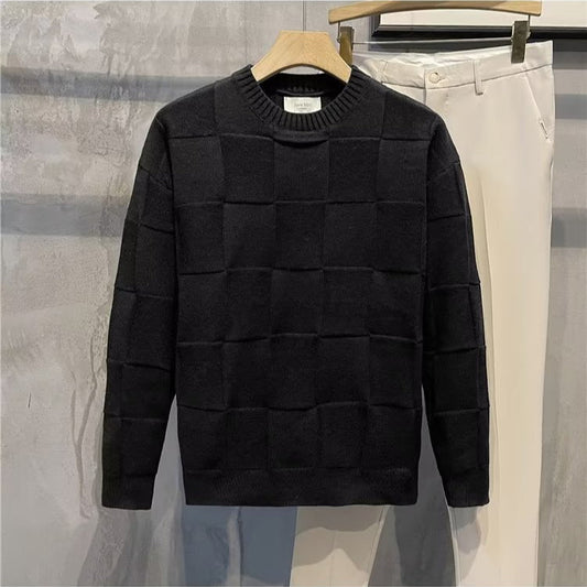 Maglione nero a quadri su gruccia, accanto a pantaloni bianchi. Moda uomo, abbigliamento casual elegante, tessuto invernale caldo.