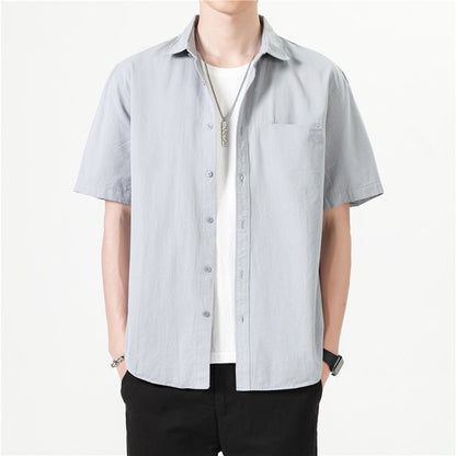 Camicia uomo a maniche corte grigia, stile casual, indossata sopra una maglietta bianca. Moda estiva, abbigliamento maschile elegante e moderno.