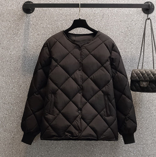 Giacca trapuntata nera appesa su gruccia, design minimalista, sfondo grigio, borsa a tracolla abbinata. Moda autunnale, abbigliamento casual.