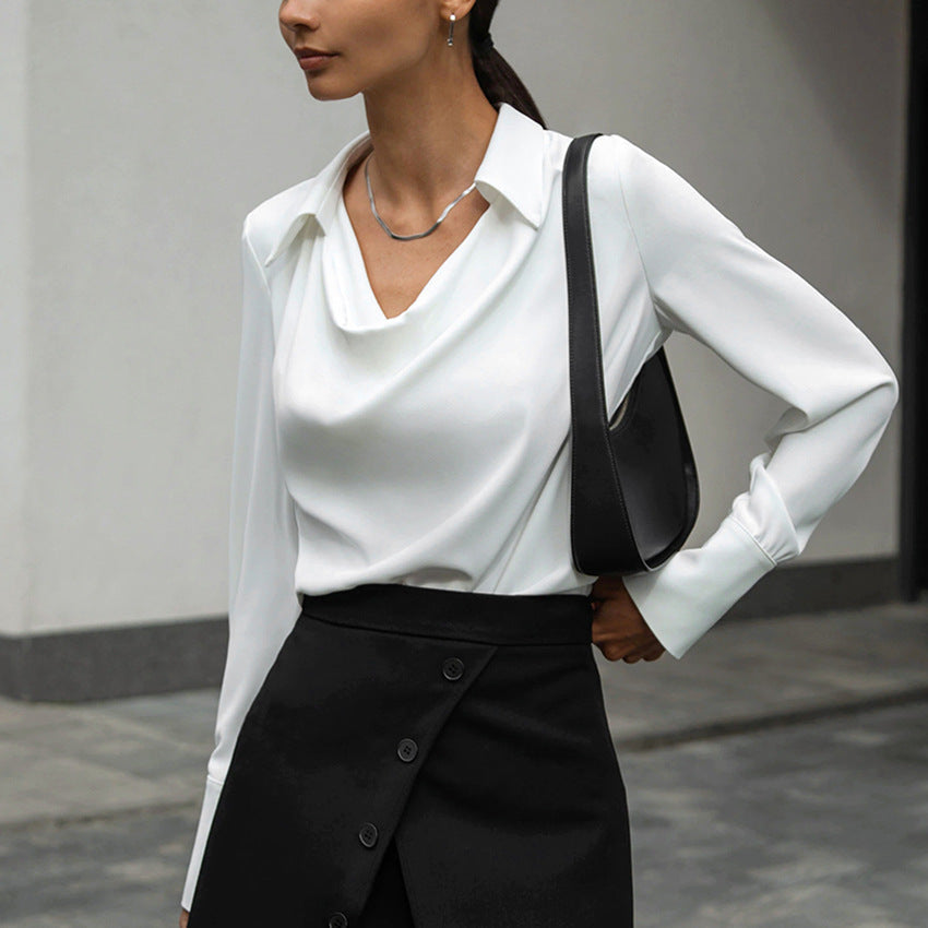 Donna con camicia bianca elegante e gonna nera asimmetrica, borsa a spalla nera. Moda minimalista, abbigliamento formale, stile contemporaneo.