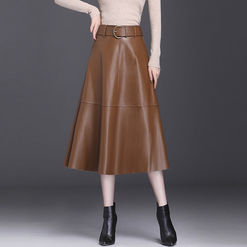 Gonna midi in pelle marrone con cintura, indossata con maglia beige e stivaletti neri. Moda autunnale elegante e chic.