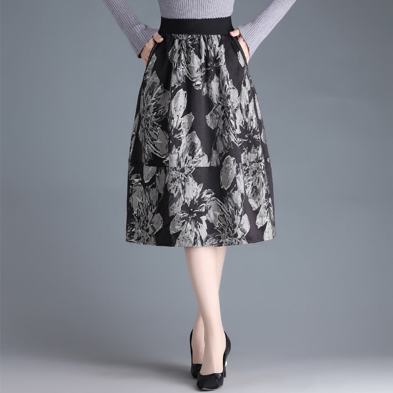 Gonna a vita alta floreale grigia e nera, indossata con maglione grigio e tacchi neri. Moda elegante donna, abbigliamento autunnale.
