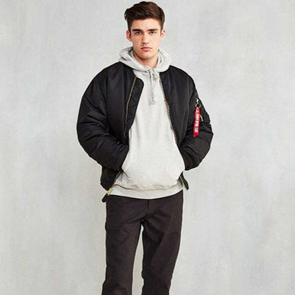 Giovane uomo con giacca bomber nera e felpa grigia, posa casual. Moda maschile, abbigliamento streetwear, stile urbano.