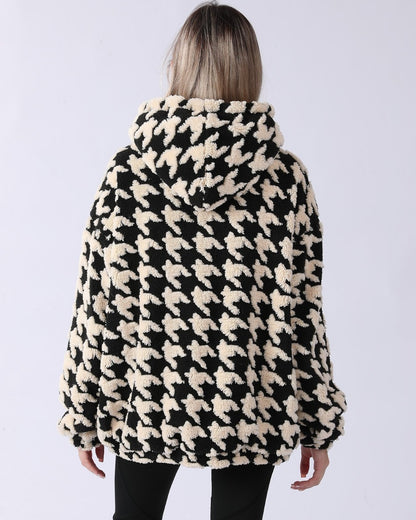 Donna con cappotto in pile a fantasia pied de poule bianco e nero, vista posteriore. Moda invernale, abbigliamento caldo e accogliente.