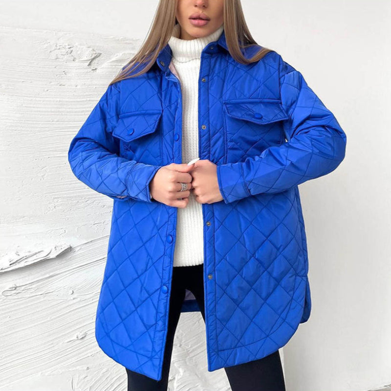 Donna con giacca trapuntata blu, camicia bianca a collo alto, sfondo bianco. Moda invernale, abbigliamento casual, stile moderno.