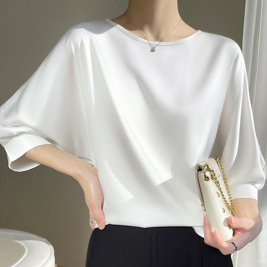 Donna con blusa bianca elegante, maniche ampie, tiene una borsa bianca. Moda minimalista, abbigliamento femminile chic, stile contemporaneo.