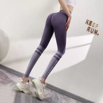 Donna in leggings sportivi viola e top bianco, scarpe da ginnastica bianche, posa accanto a muro con scritta "Keep Run". Fitness, abbigliamento sportivo.
