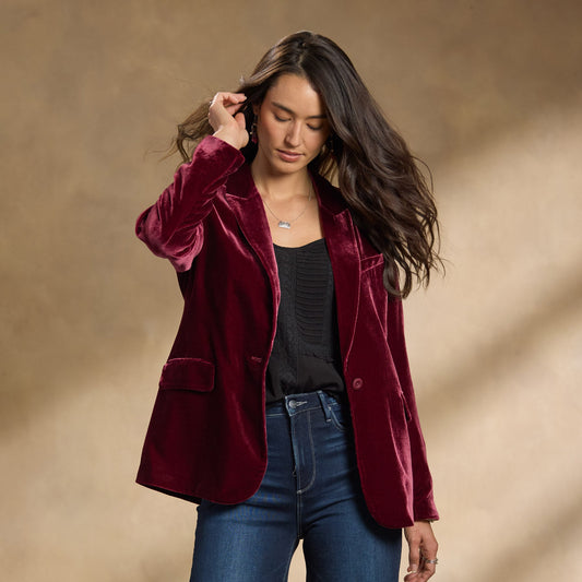 Donna con giacca di velluto bordeaux, camicia nera e jeans blu. Moda autunno, abbigliamento elegante casual, tendenze femminili 2023.