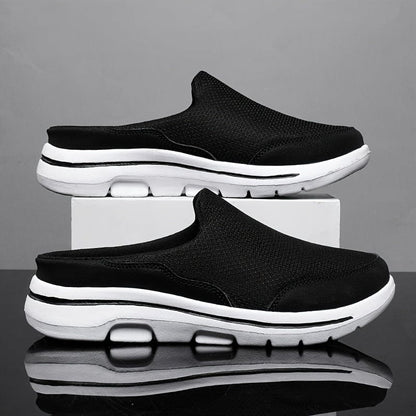 Scarpe slip-on nere da uomo su sfondo grigio, suola bianca ammortizzata, design casual e sportivo, ideali per comfort e stile quotidiano.