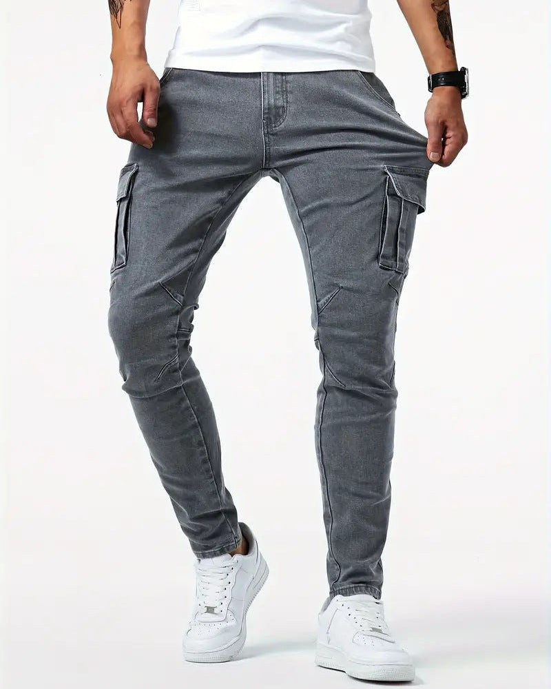 Jeans cargo grigi da uomo, vestibilità slim, con tasche laterali, abbinati a scarpe da ginnastica bianche e maglietta bianca.