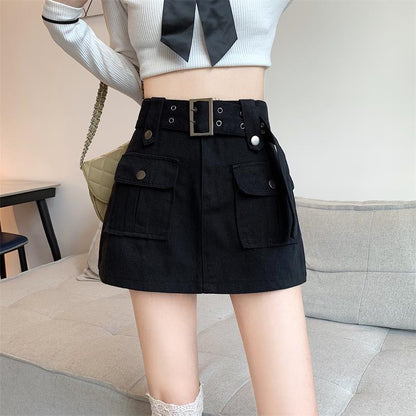Donna in minigonna nera con tasche e cintura, maglia bianca a coste con fiocco nero, posa in salotto moderno. Moda femminile, abbigliamento casual.