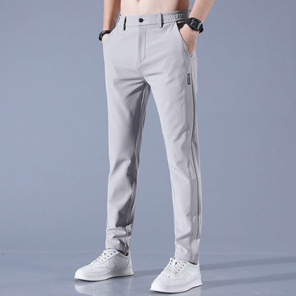 Pantaloni grigi da uomo eleganti, vestibilità slim, con tasche laterali, abbinati a scarpe bianche sportive. Ideali per look casual e formali.
