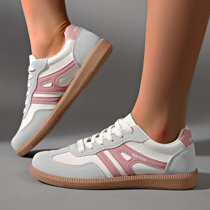 Scarpe da ginnastica bianche e rosa con suola in gomma marrone, design moderno, indossate su sfondo grigio. Sneakers moda donna, calzature casual.