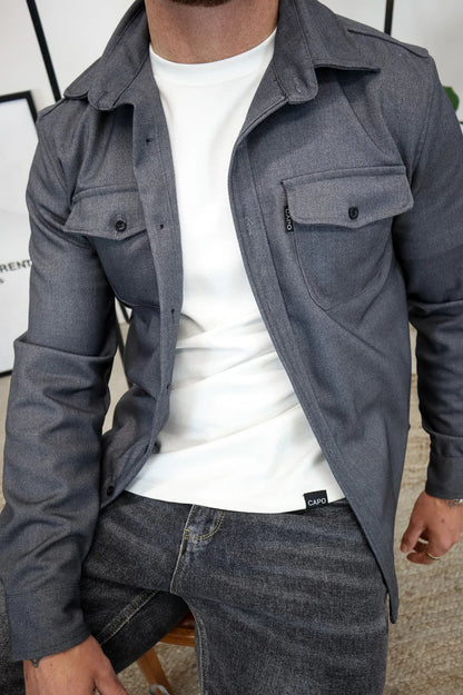 Uomo con camicia grigia in tessuto pesante, indossa maglietta bianca e jeans scuri. Moda casual maschile, abbigliamento autunnale elegante.