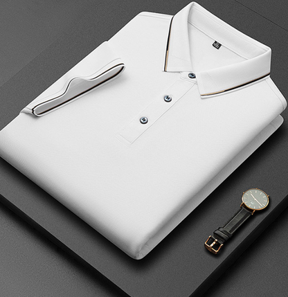 Camicia polo bianca piegata su sfondo nero, con dettagli a righe sul colletto e polsini. Orologio elegante con cinturino in pelle accanto.