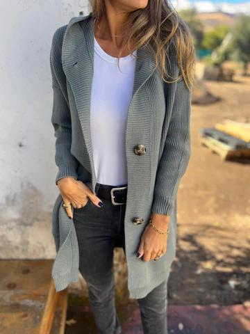 Donna con cardigan grigio lungo, maglietta bianca e jeans neri. Moda autunnale casual, abbigliamento femminile elegante e confortevole.