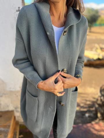 Donna indossa cardigan grigio in maglia con bottoni grandi, tasche frontali, su sfondo esterno sfocato. Moda autunnale, abbigliamento casual elegante.