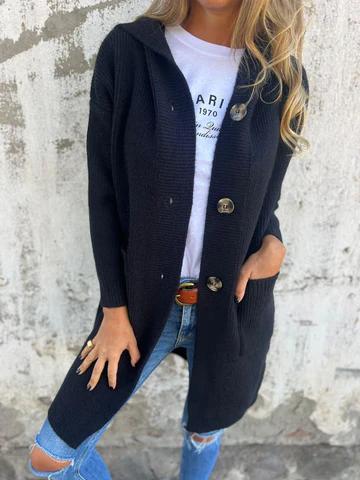 Donna con cardigan nero lungo, bottoni grandi, indossa jeans strappati e maglietta bianca. Moda casual autunnale, stile urbano chic.