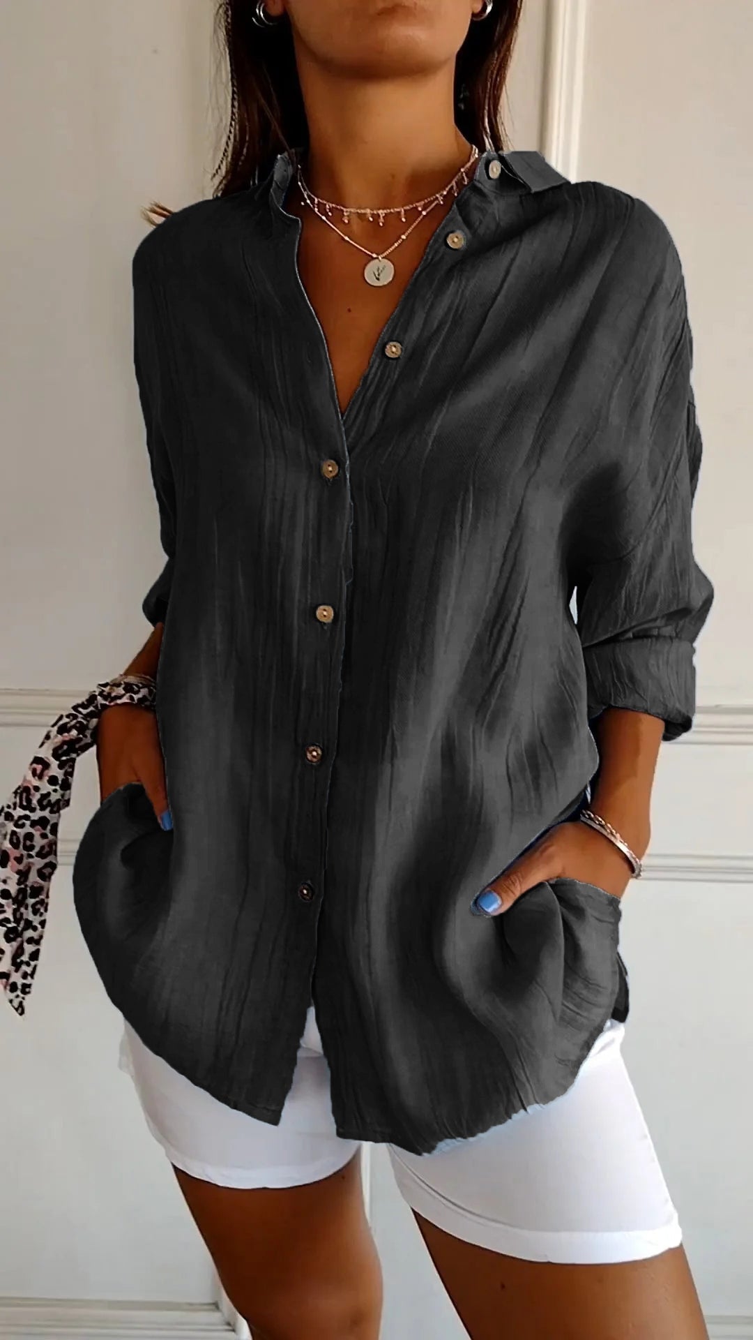 Donna con camicia nera elegante, maniche lunghe, bottoni in legno, abbinata a pantaloni bianchi. Stile casual chic, moda femminile contemporanea.