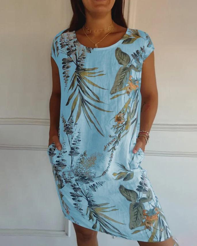 Donna con abito estivo azzurro a fiori tropicali, maniche corte, tasche laterali. Moda femminile, abbigliamento casual elegante.