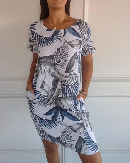Abito estivo donna con stampa foglie tropicali blu su sfondo bianco, maniche corte, tasche laterali. Moda casual, stile fresco e leggero.
